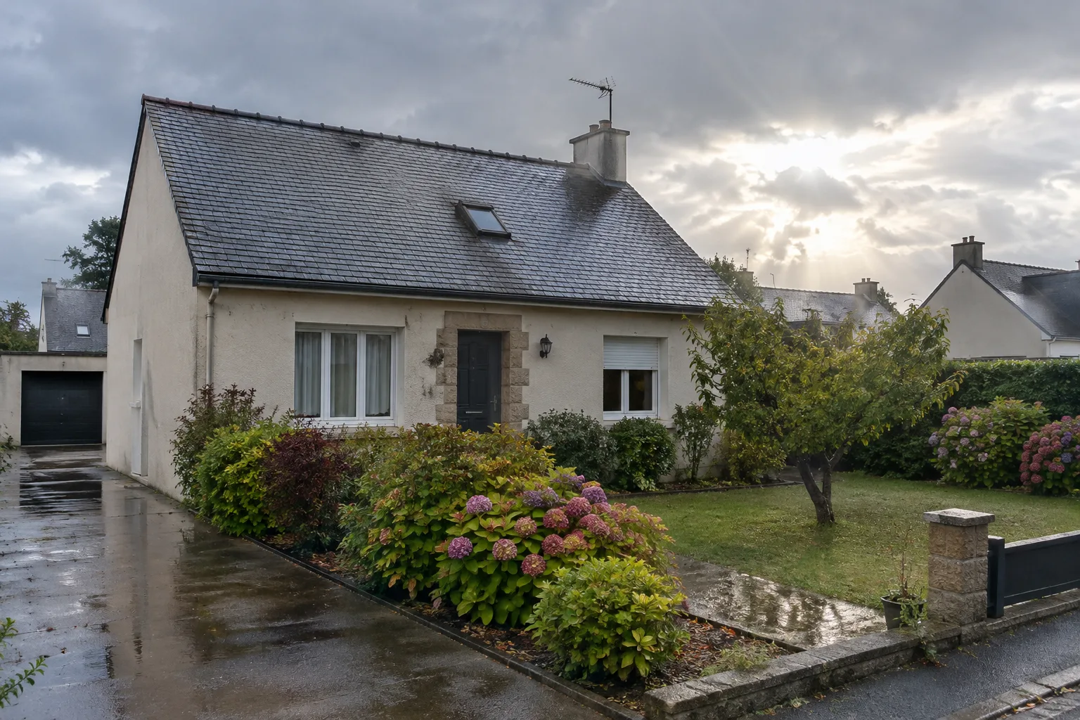 Maison dans un quartier résidentiel après une forte pluie, sous un ciel encore couvert.